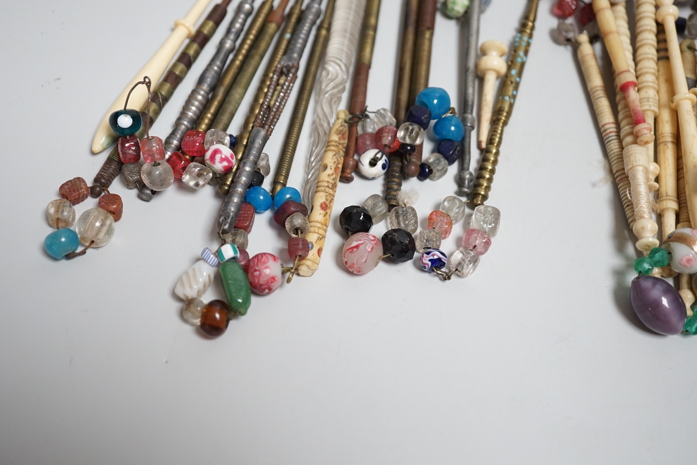 Twenty ornate 19th century turned bone and beaded topped lace bobbins and eleven ornately turned metal lace bobbins, glass bobbin and 3 broken bobbins (34)